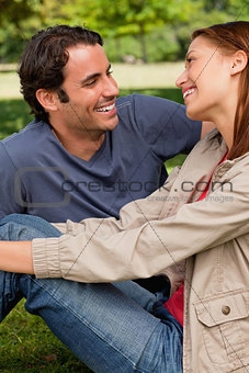 Two friends laughing while they are both sitting on the grass
