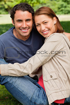 Two friends smiling and looking in front of them as they sit nex