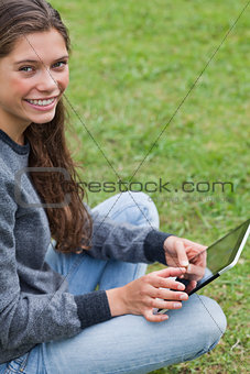 Young smiling girl sitting down with her tablet pc while looking