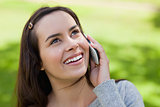 Young smiling woman talking on the phone while looking up