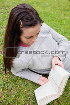 Young woman reading a book while lying on the grass