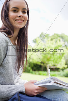 Young smiling girl looking at the camera while doing her homewor