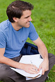 Young smiling man looking away while working on the grass