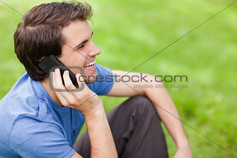 Young man talking on the phone while sitting on the grass