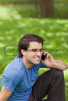 Young smiling man calling with his cellphone while sitting in a 