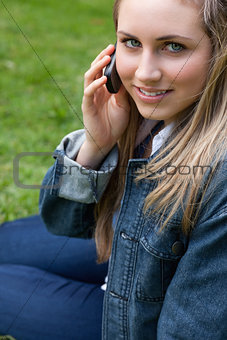 Young smiling girl talking on the phone while sitting down in a 