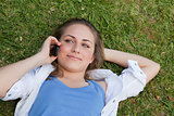 Young relaxed blonde girl lying on her back while talking on the