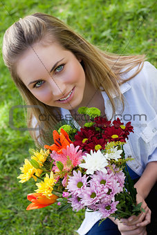 Attractive blonde teenager holding a beautiful bunch of flower