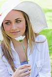 Young peaceful girl holding a white flower in a park