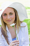 Young blonde girl wearing a white hat while holding a white flow