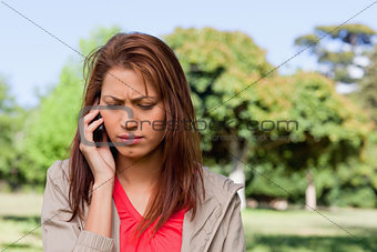 Woman looking towards the ground while on the phone in a bright 