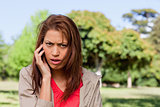 Woman with a serious expression talking on the phone in a bright