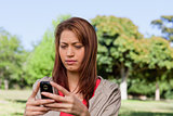 Serious woman reading a text message in a bright grassland area