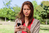 Woman with a stern expression on her face while holding a phone