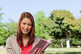 Woman smiling while looking straight ahead with a book in her ha