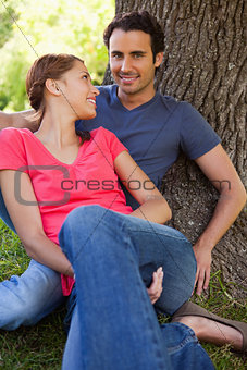 Woman looking at her friend while they sit together in the shade