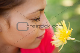Woman closes her eyes as she smells a yellow flower