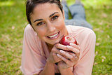 Woman looking ahead while holding an apple