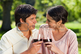 Two friends looking at each other while touching glasses of wine
