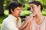 Two friends drinking wine while linking arms