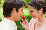 Woman smiling while offering a strawberry to her friend