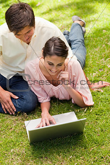 Woman resting her face against her hand while using a laptop wit
