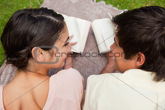 Rear view of two friends looking at each other while reading on 