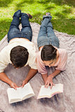 Elevated view of two friends reading while on a lying down