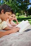 Woman looking to the side as she reads with her friend in a park