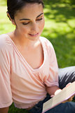 Woman smiling while reading a book as she sits on grass