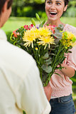 Woman surprised as she is presented with flowers by her friend
