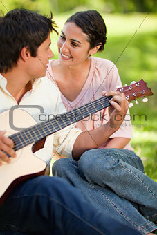 Man playing a guitar while looking at his friend
