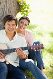 Woman smiling with her friend who is holding a guitar