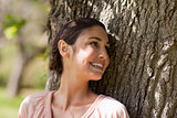 Woman looking over her shoulder while sitting against a tree