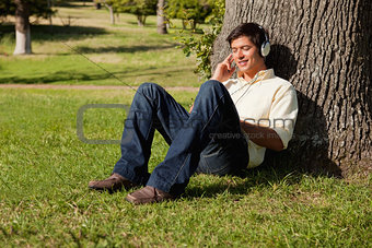 Man smiling while listening to music through headphones while re