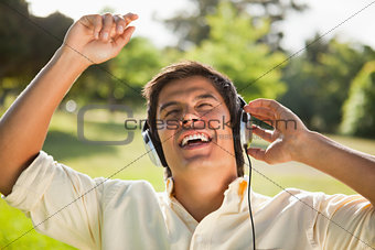 Man raising his arms while using headphones to sing along to mus