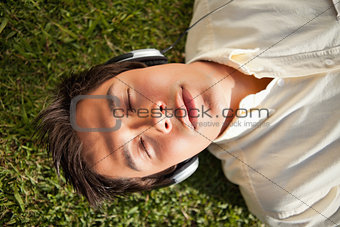Man closes his eyes while using headphones to listen to music as