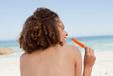 Smiling attractive woman holding an orange ice lolly 
