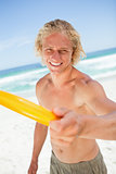 Smiling man playing frisbee while standing on the beach
