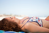 Side view of a young woman napping on a beach towel