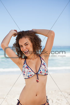 Smiling young woman raising her arms above the head in front of 