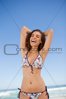 Young woman sunbathing on the beach while laughing