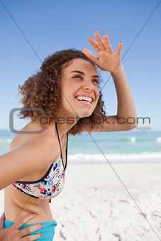 Happy young woman placing her hand on her forehead to look far a