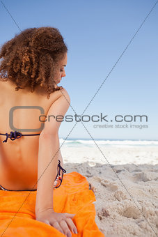 Rear view of a young woman sitting on a beach towel