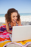 Young attractive woman using a laptop on the beach while laughin