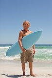 Blonde man holding his surfboard while standing in front of the 