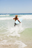 Blonde man running fast in the water while holding his surfboard