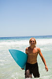 Blonde man walking in the water while showing a beaming smile