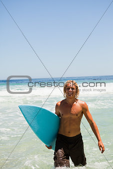 Blonde man walking in the water while showing a beaming smile