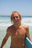 Smiling man standing in the water while holding his surfboard